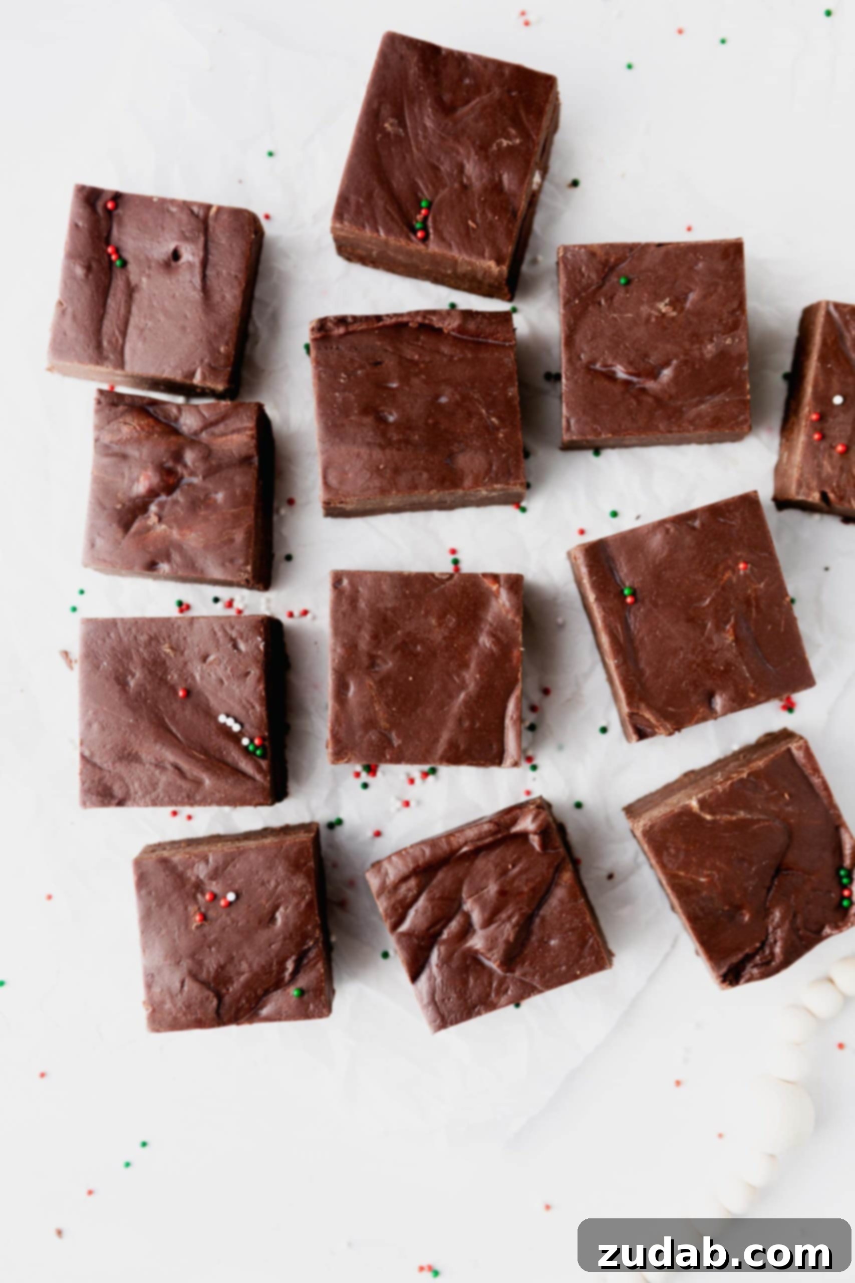 Best Fudge Recipe 12 square pieces of fudge on a piece of parchment paper.