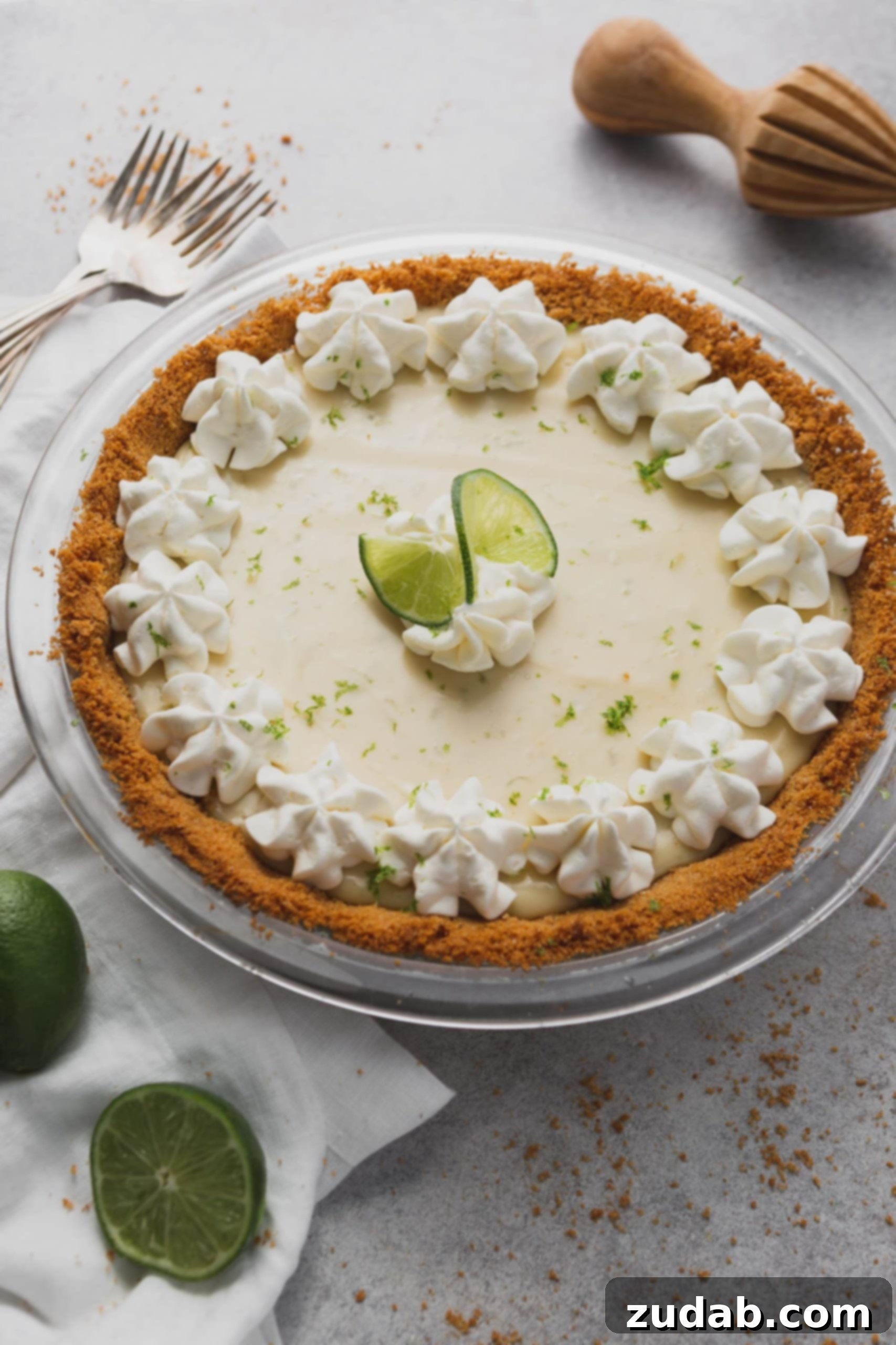 Key Lime Pie Recipe A key lime pie in a graham cracker crust. The top is decorated with whipped cream and slices of lime.