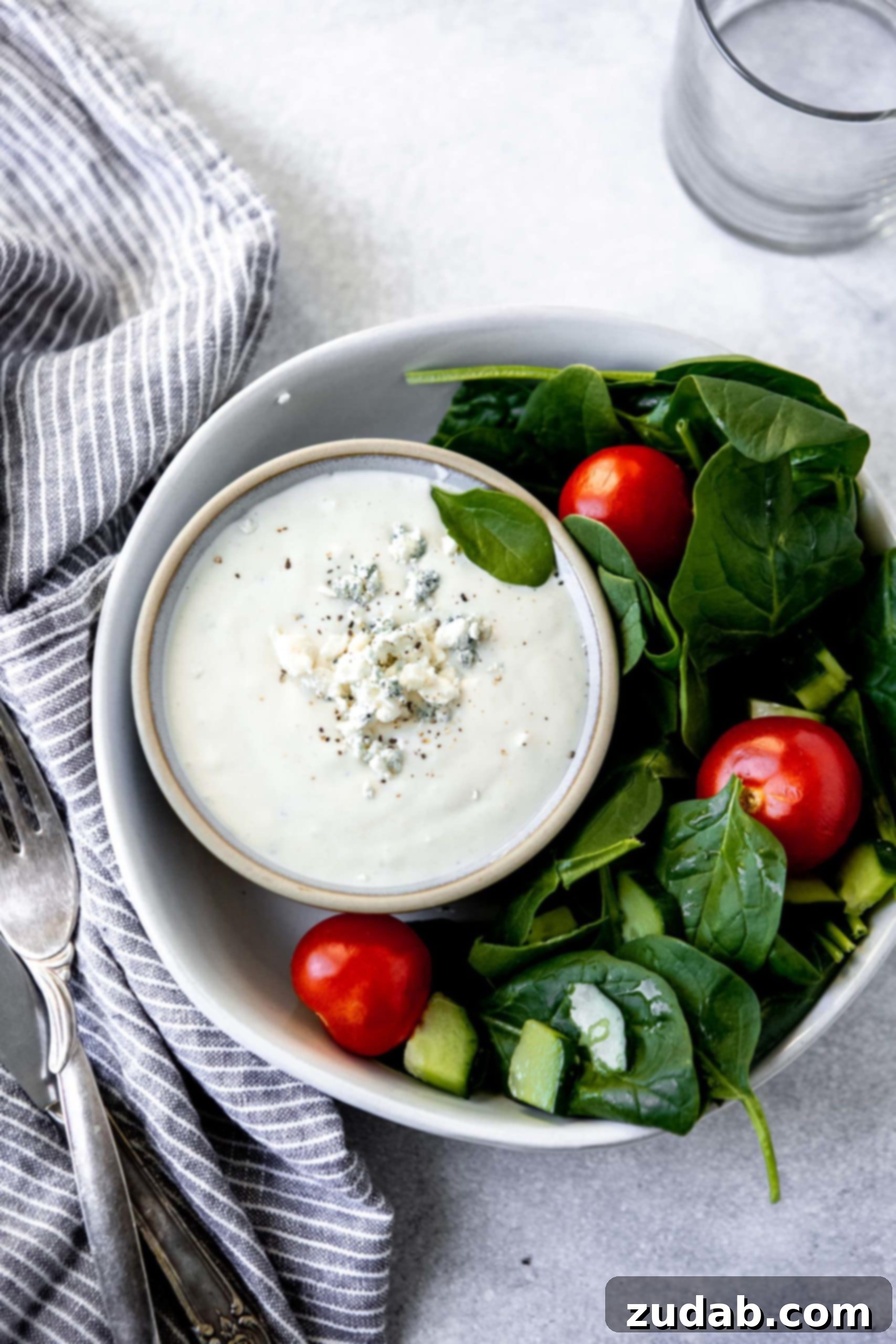 Blue Cheese Dressing a photo of a green salad in a white bowl with a cup of blue cheese dressing in the bowl