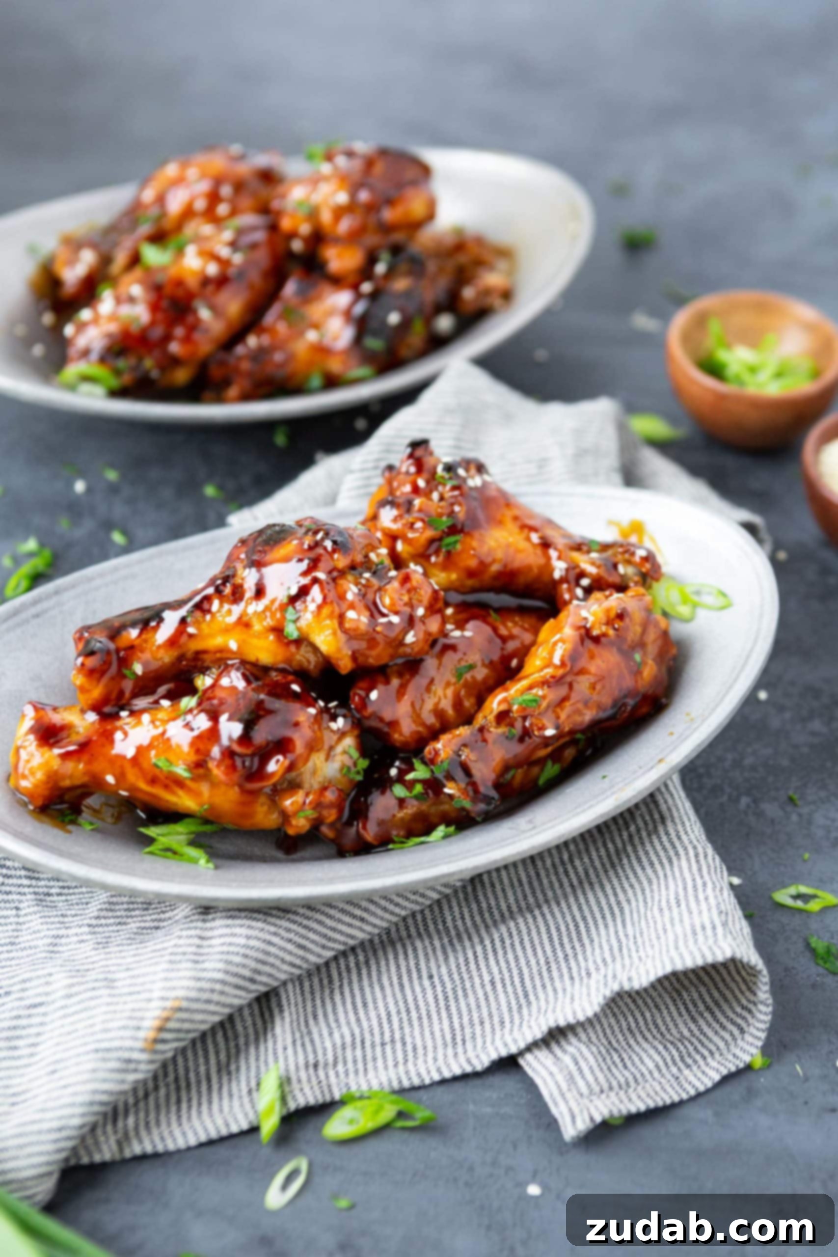 Air Fryer Teriyaki Chicken Wings a photo of several baked chicken wings glazed in teriyaki sauce on a white platter.