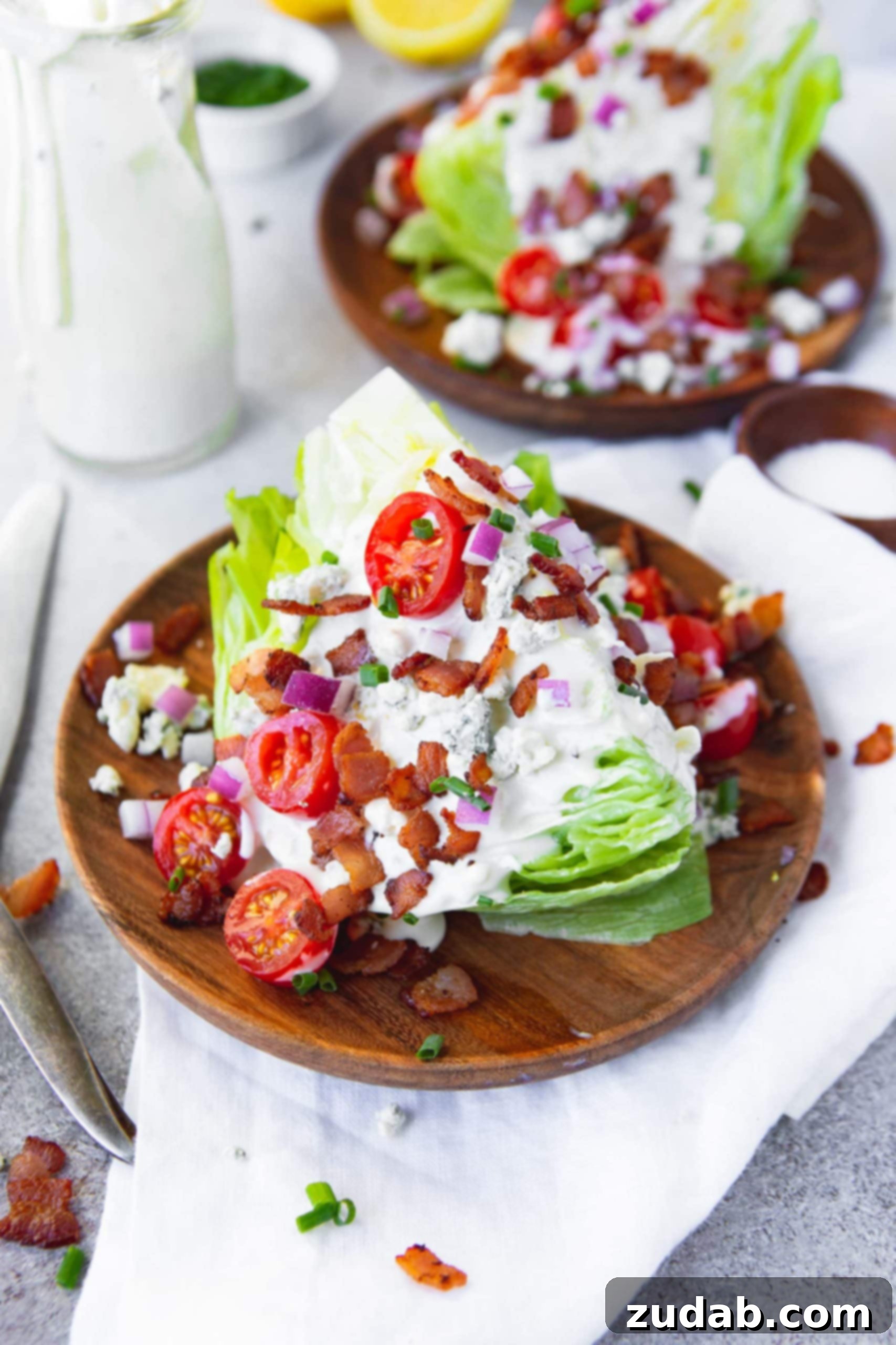 How to Enjoy a Wedge Salad A beautifully garnished wedge salad featuring creamy blue cheese dressing, crispy bacon bits, chopped fresh chives, diced red onions, halved cherry tomatoes, and crumbled blue cheese, ready to be enjoyed as a perfect side or light meal.
