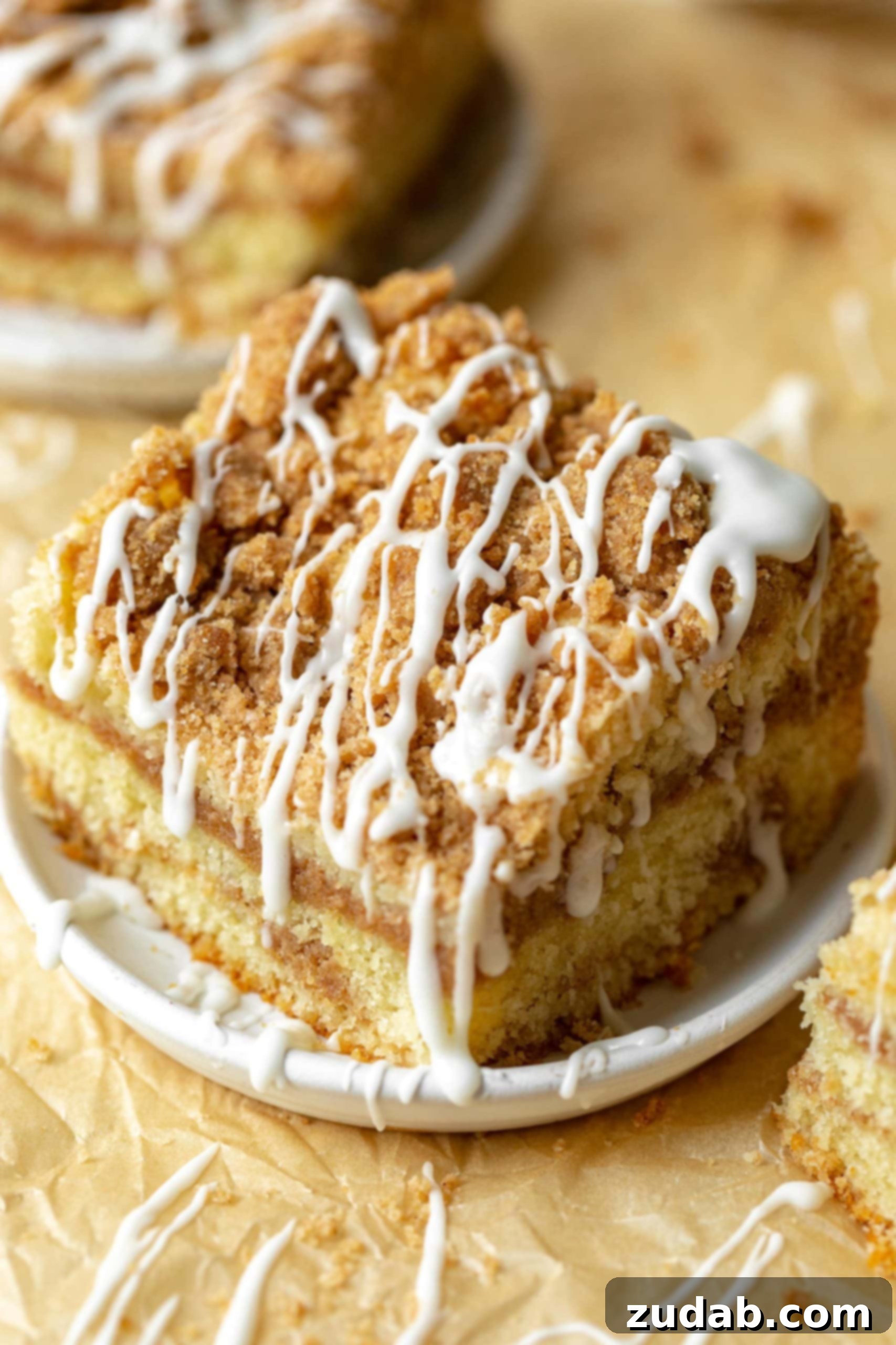 The Coffee Cake That Makes Starbucks Seem Basic 3 a photo of a piece of coffee cake topped with a cinnamon streusel and drizzles of icing.