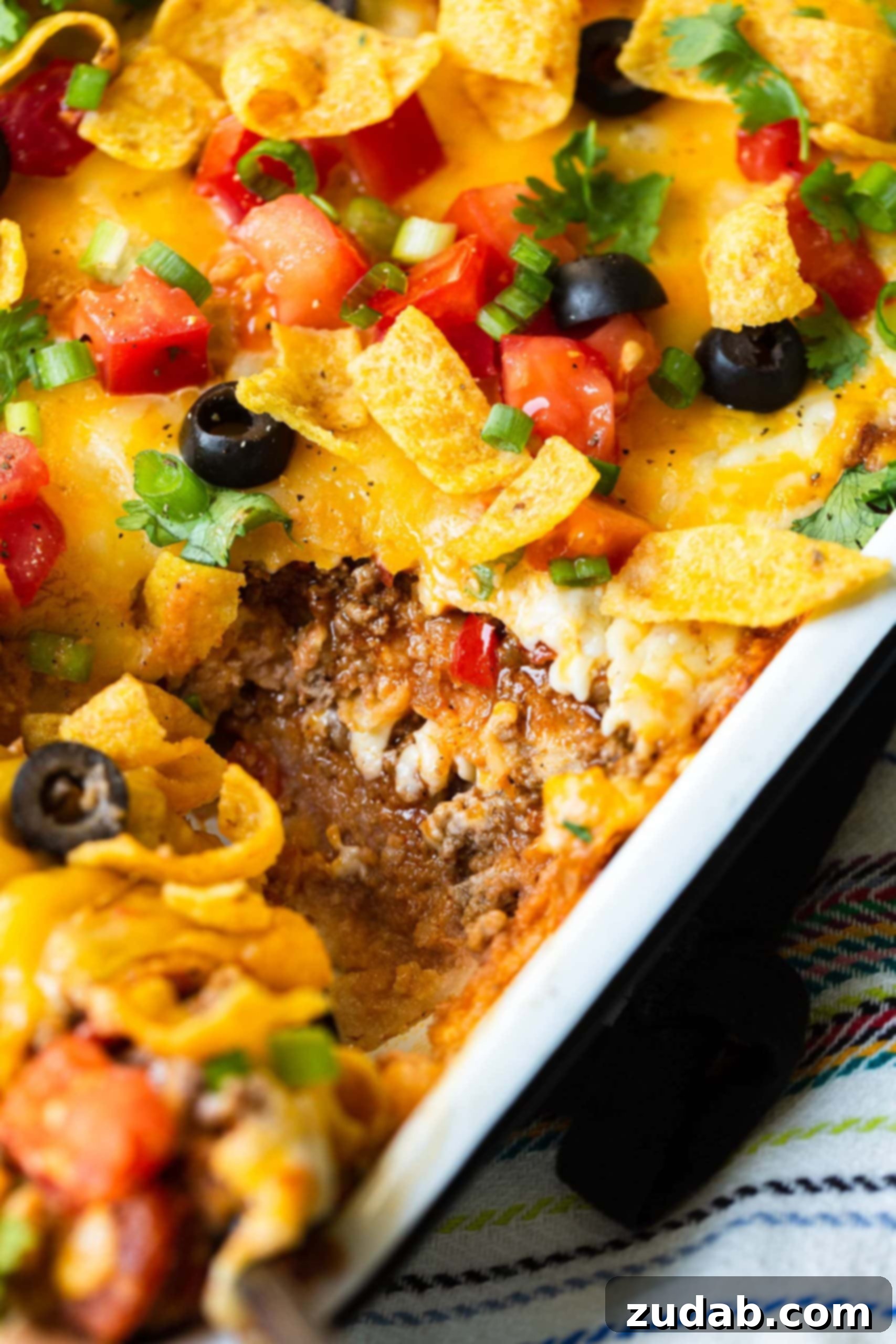 Speedy Fiesta Taco Bake 2 A close-up photo of a taco casserole in a baking dish, with one slice removed to show the distinct, savory layers within.