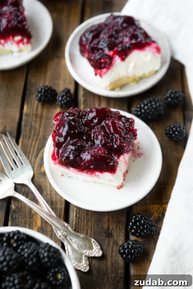 Berry Bliss Cheesecake Bars 5 a couple of white plates with an almost no bake cheesecake and berry sauce