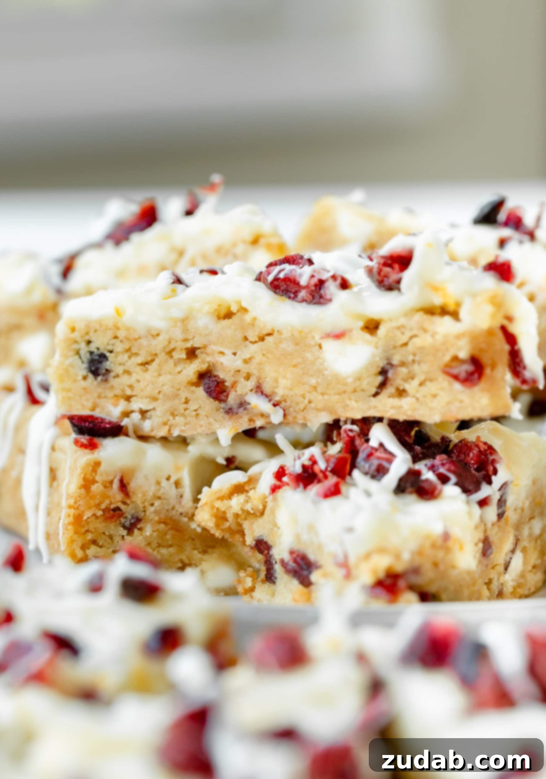 a photo of two orange cranberry bliss bars that have been cut into triangles and then stacked on top of each other so you can see the cross section of the blondies.