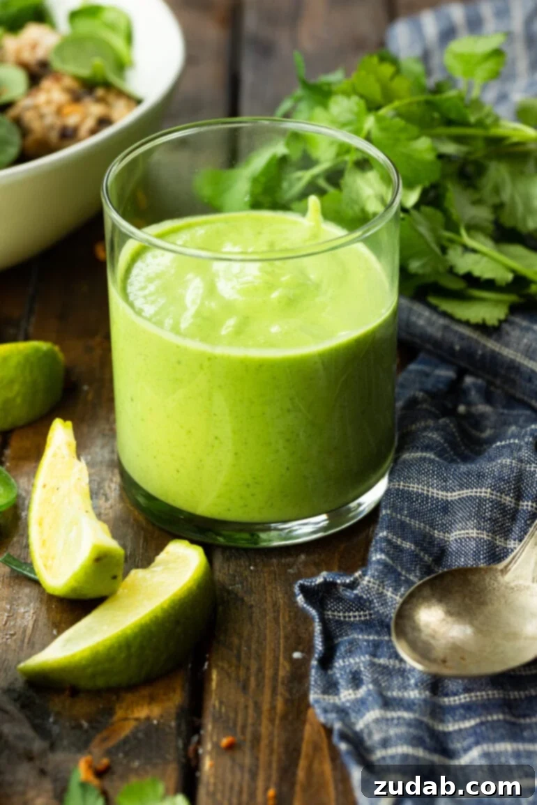 Fresh Creamy Avocado Cilantro Lime Dressing 3 A close-up photo of a glass cup filled with bright green avocado cilantro lime dressing, showcasing its creamy texture.