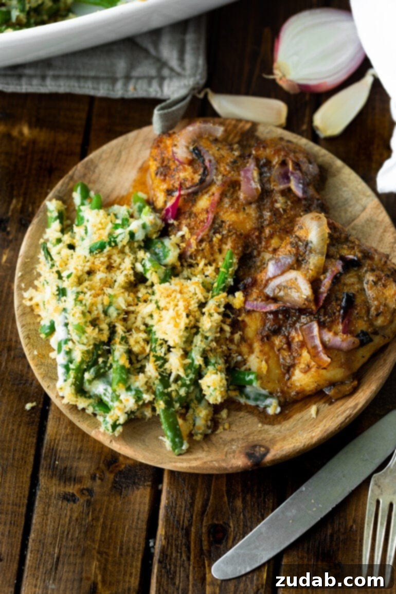 Ultimate Ranch Green Beans 7 a photo of a wooden plate with two roasted chicken thighs sitting next to a helping of creamy ranch green beans topped with crunchy golden panko.