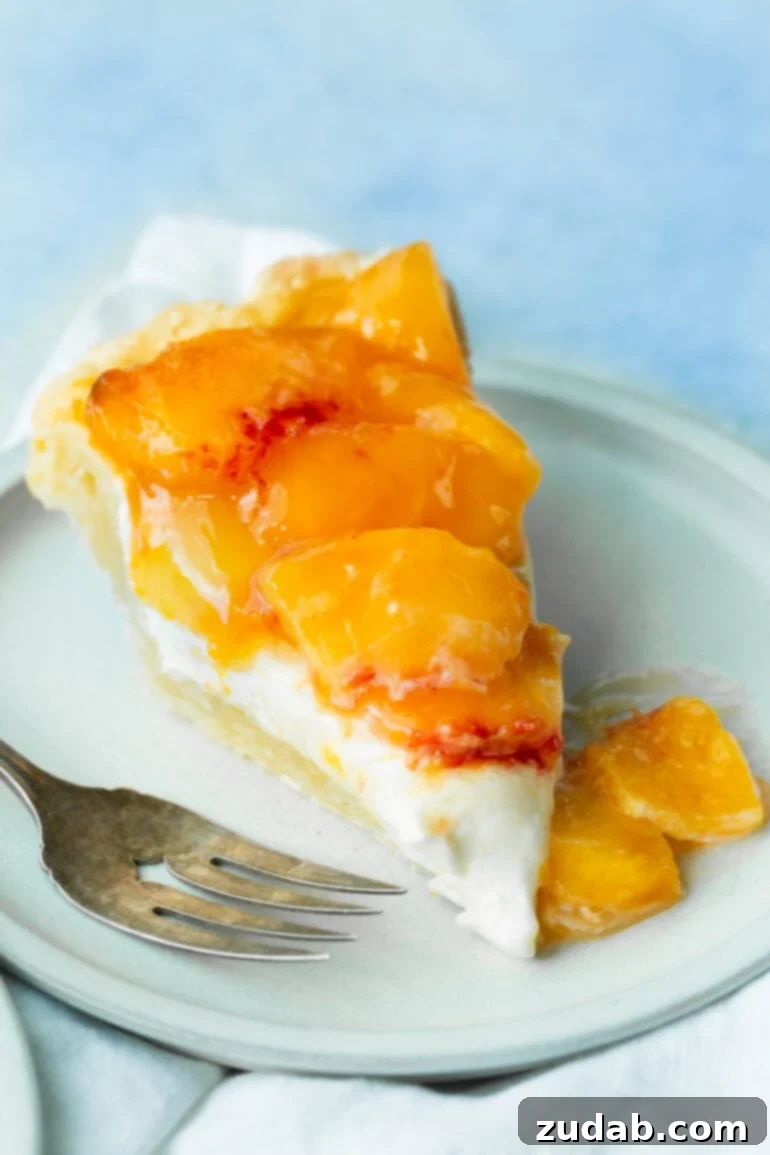 Peaches and Cream Pie Perfection 2 A perfectly sliced piece of peaches and cream pie, revealing layers of golden-brown crust, creamy white filling, and vibrant orange peaches, ready to be enjoyed.