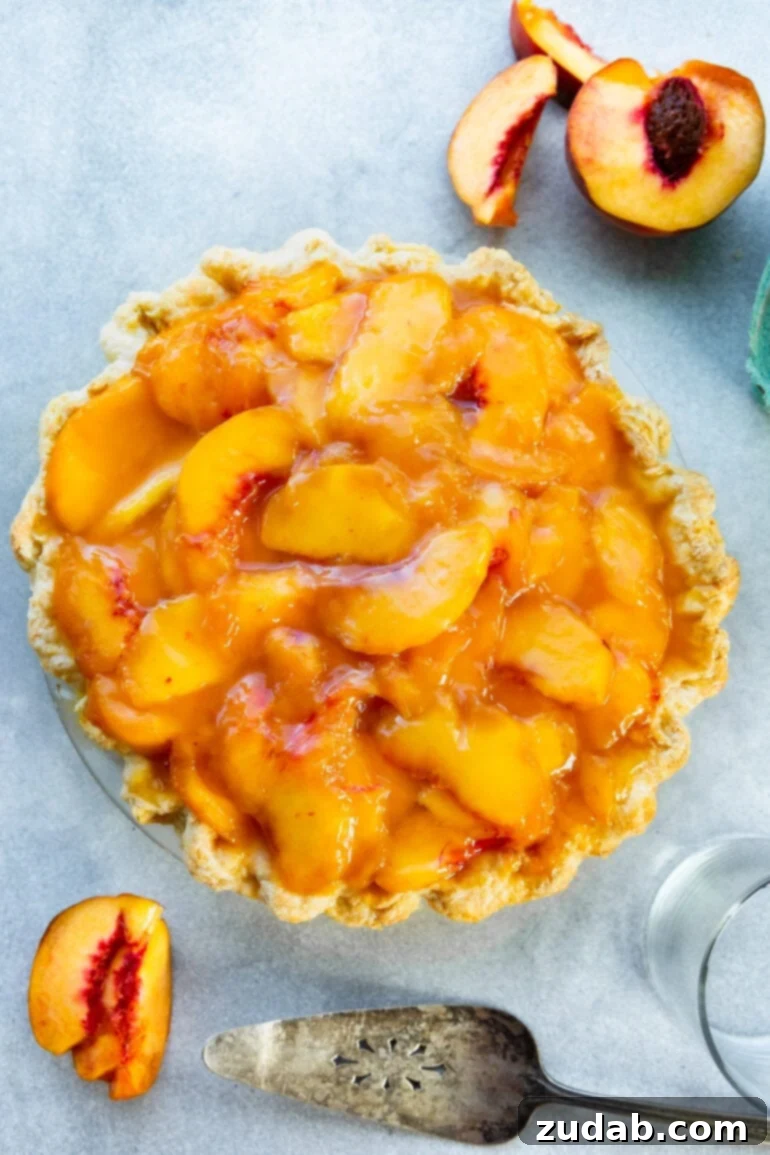 Peaches and Cream Pie Perfection 3 A stunning whole peaches and cream pie, featuring a golden, crimped homemade crust generously topped with glistening, bright orange peach slices, promising a delightful treat.