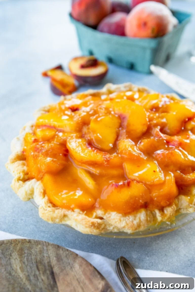 Peaches and Cream Pie Perfection 4 A vibrant whole peaches and cream pie showcasing a perfectly baked golden crust, generously covered with a thick, saucy layer of fresh peach slices over a creamy base.