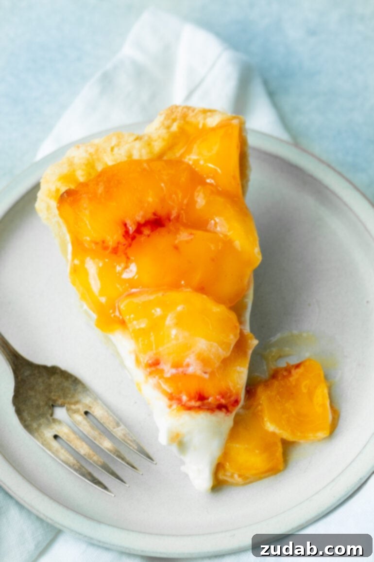 Peaches and Cream Pie Perfection 5 An inviting overhead shot of a single slice of peaches and cream pie, adorned with generous peach slices and a dollop of fresh cream on top, ready for a blissful bite.