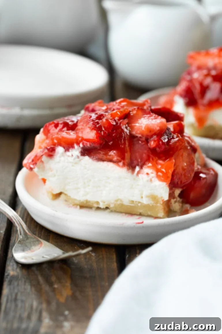 Luscious Strawberry Cheesecake Squares 2 A photo of a single, perfectly square piece of creamy strawberry cheesecake bar, adorned with glistening fresh strawberries, resting on a small white dessert plate, ready to be enjoyed.