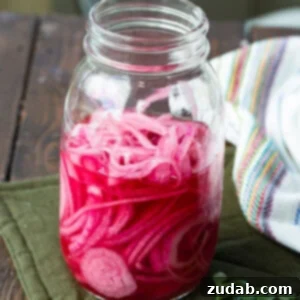 A vibrant image of quick pickled red onions in a jar, ready to be served.