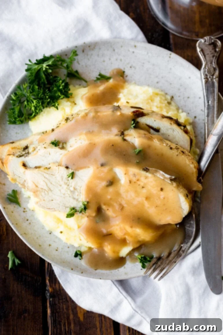 A glistening, homemade turkey gravy, generously poured over a mound of creamy mashed potatoes, embodying the warmth and flavor of holiday feasts.