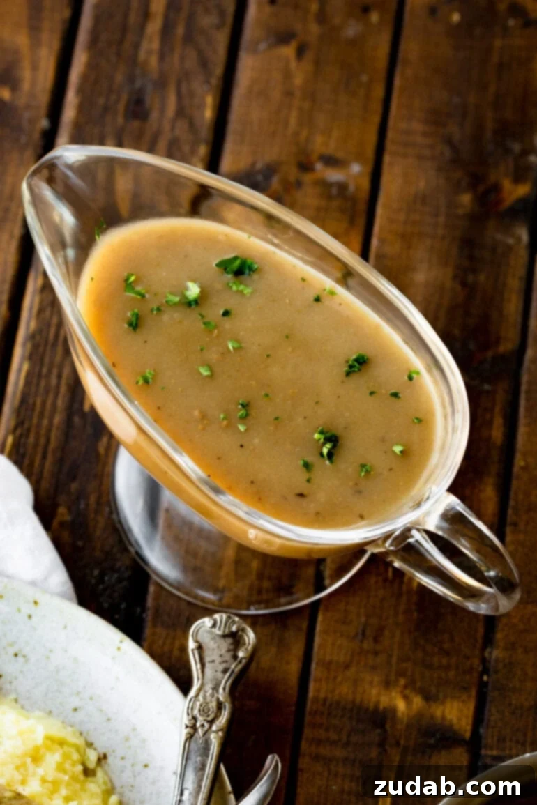 A elegant clear glass gravy boat, brimming with smooth, rich turkey gravy, garnished with a sprinkle of fresh chopped parsley, ready to be served.