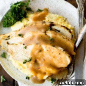 A photo taken over the top of a plate full of mashed potatoes topped with creamy turkey gravy