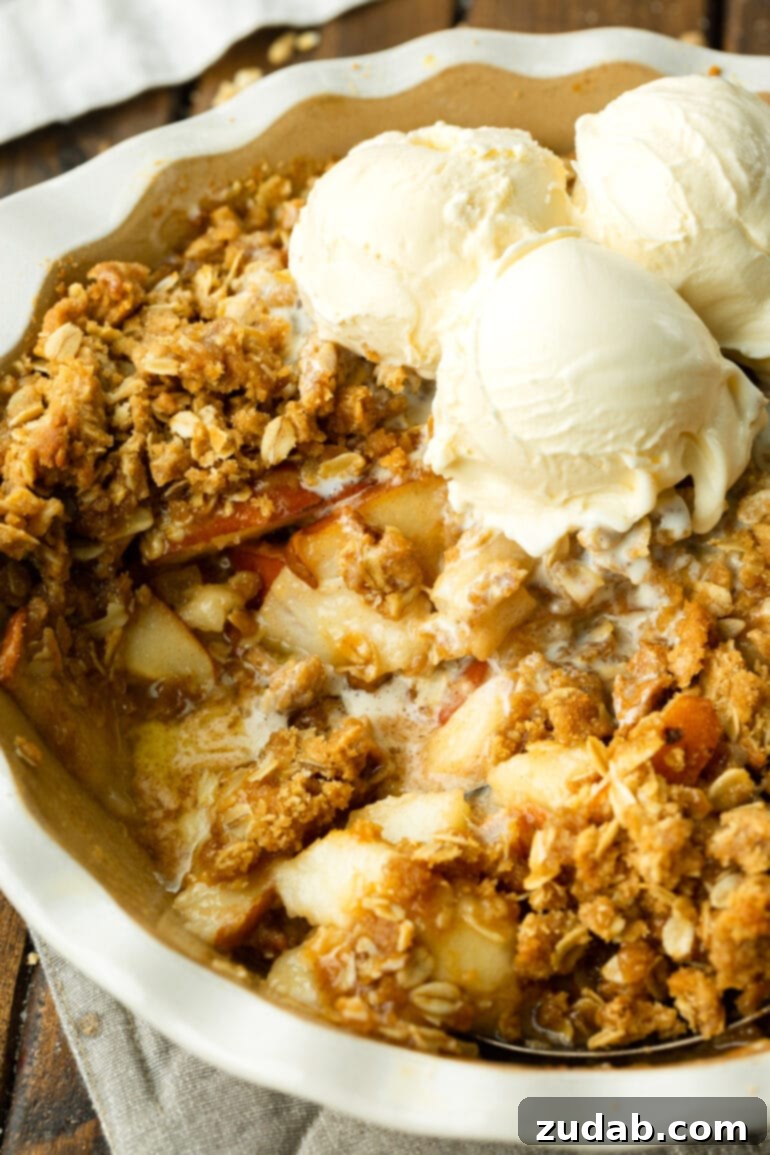 Heavenly Pear Crisp 3 A vibrant photo of a round baking dish brimming with freshly baked pear crisp, topped with melting vanilla ice cream and a serving scooped out.