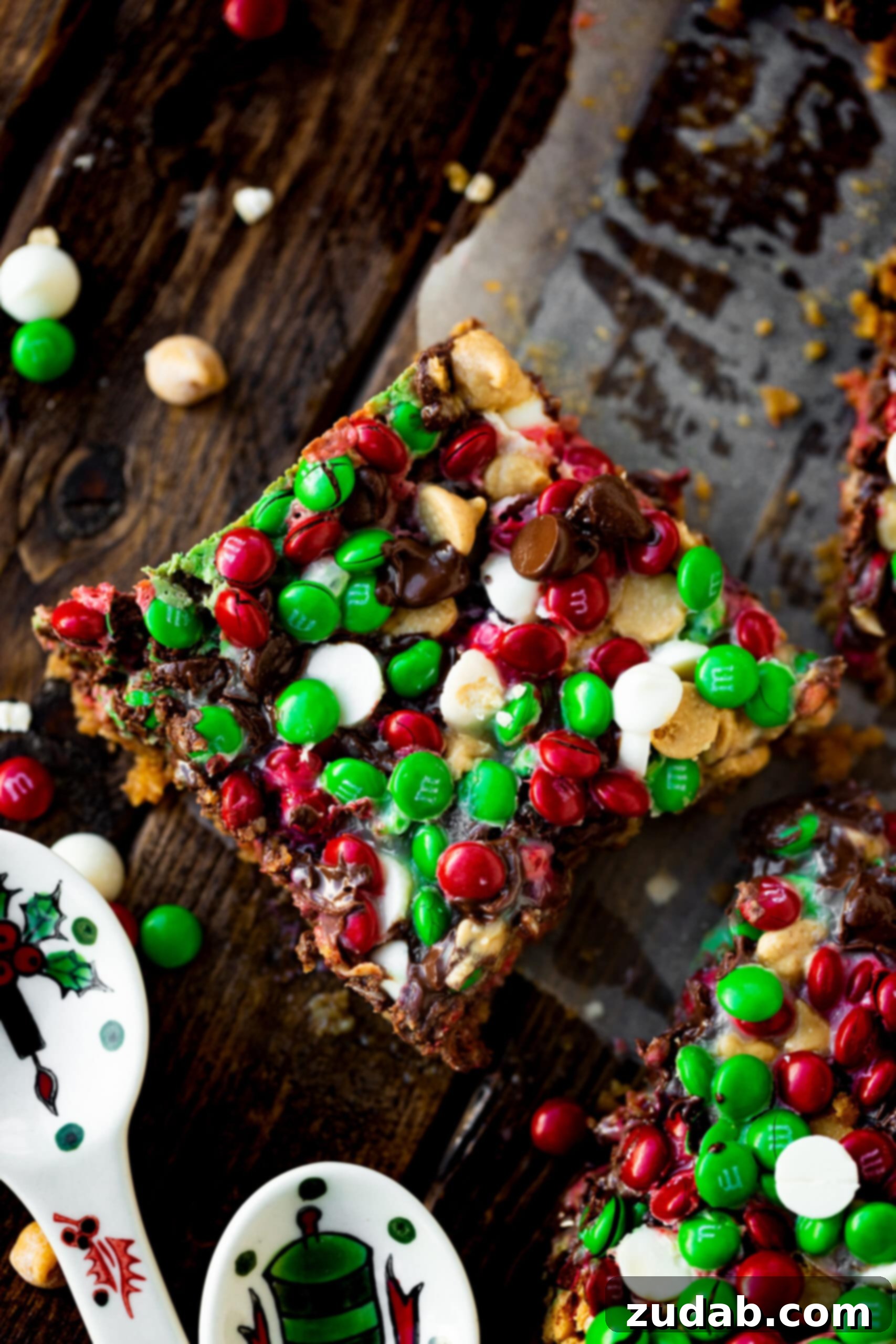 Christmas Magic Cookie Bars A photo of a large magic cookie bar topped with holiday M&M's, white chocolate chips, peanut butter chocolate chips, and semi-sweet chocolate chips.