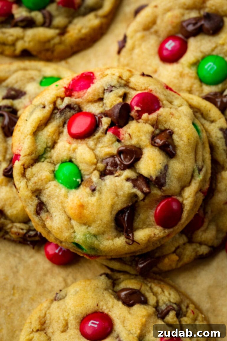 A large, perfectly baked chocolate chip cookie adorned with festive red and green Christmas M&M's, ready for the holidays.