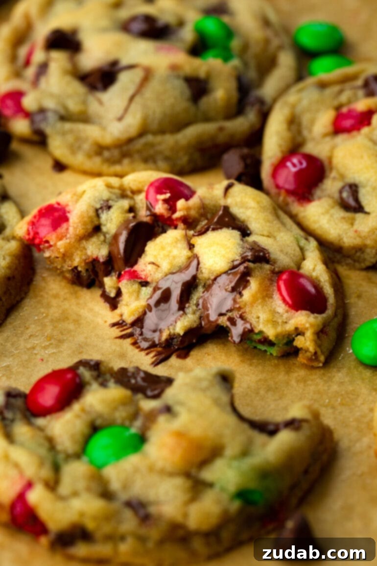 A gooey M&M chocolate chip cookie broken apart, showcasing its melted chocolate chips and soft, irresistible center – a true Christmas delight.