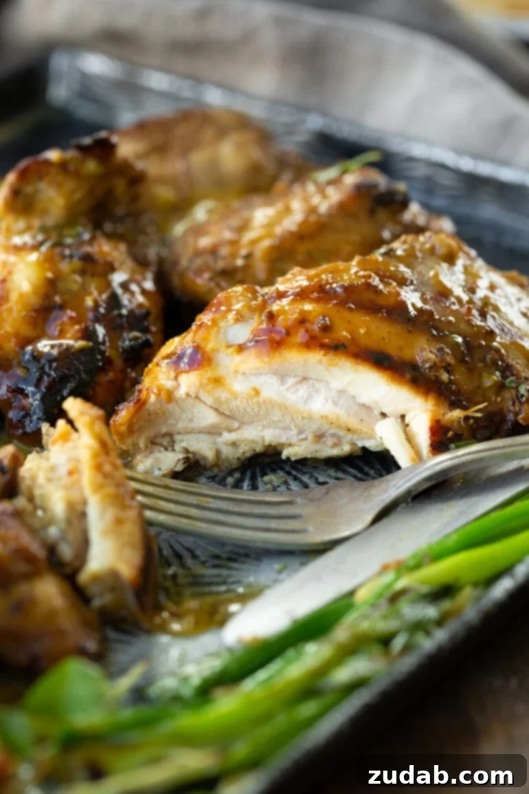Maple Mustard Glazed Grilled Chicken Thighs 4 A close-up of a perfectly grilled chicken thigh, cut open to reveal its incredibly juicy cross-section, glazed with a glistening maple mustard marinade.