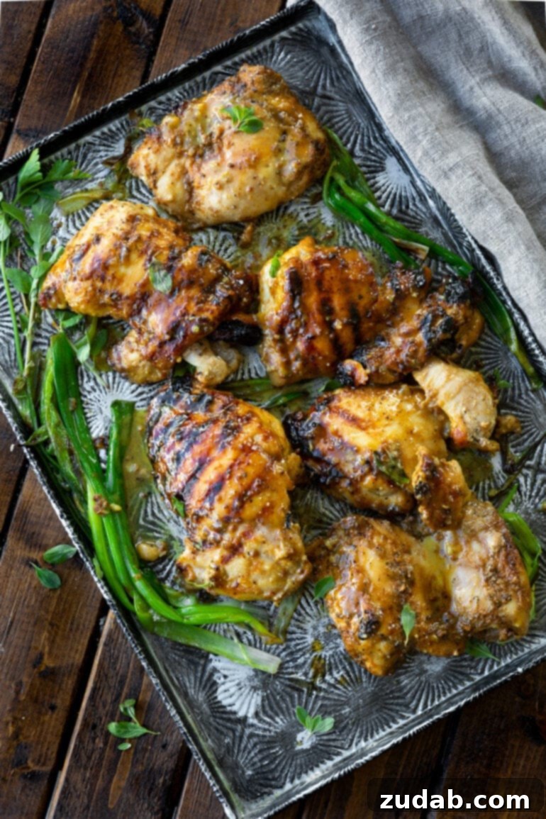 Maple Mustard Glazed Grilled Chicken Thighs 6 A baking sheet laden with several exquisitely grilled chicken thighs, each glazed to perfection with a sticky, savory maple mustard marinade, showcasing their irresistible texture.