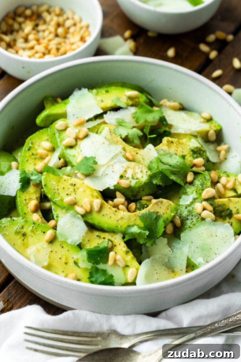Quick Avocado Delight 5 A close-up photo of a vibrant avocado salad, glistening with a tangy vinaigrette dressing, beautifully mixed with crunchy pine nuts and savory Manchego cheese, ready to be enjoyed as a refreshing side.