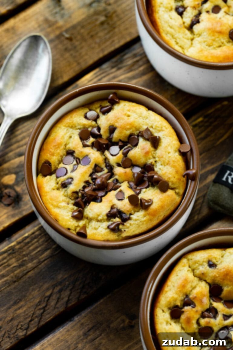 Choc Chip Cookie Protein Mug Bake 4 Several mugs of baked oatmeal, each topped with a generous sprinkle of mini chocolate chips.