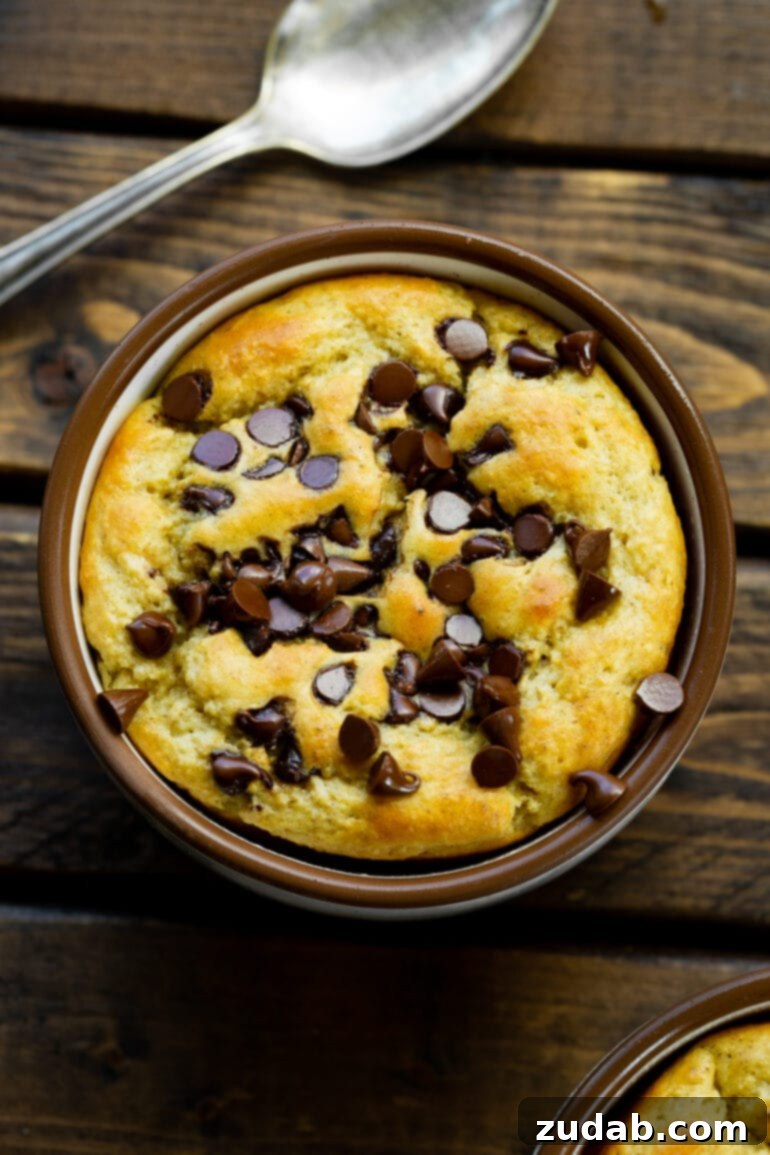 Choc Chip Cookie Protein Mug Bake 6 A top-down shot of a golden baked oatmeal in a mug, adorned with mini chocolate chips.
