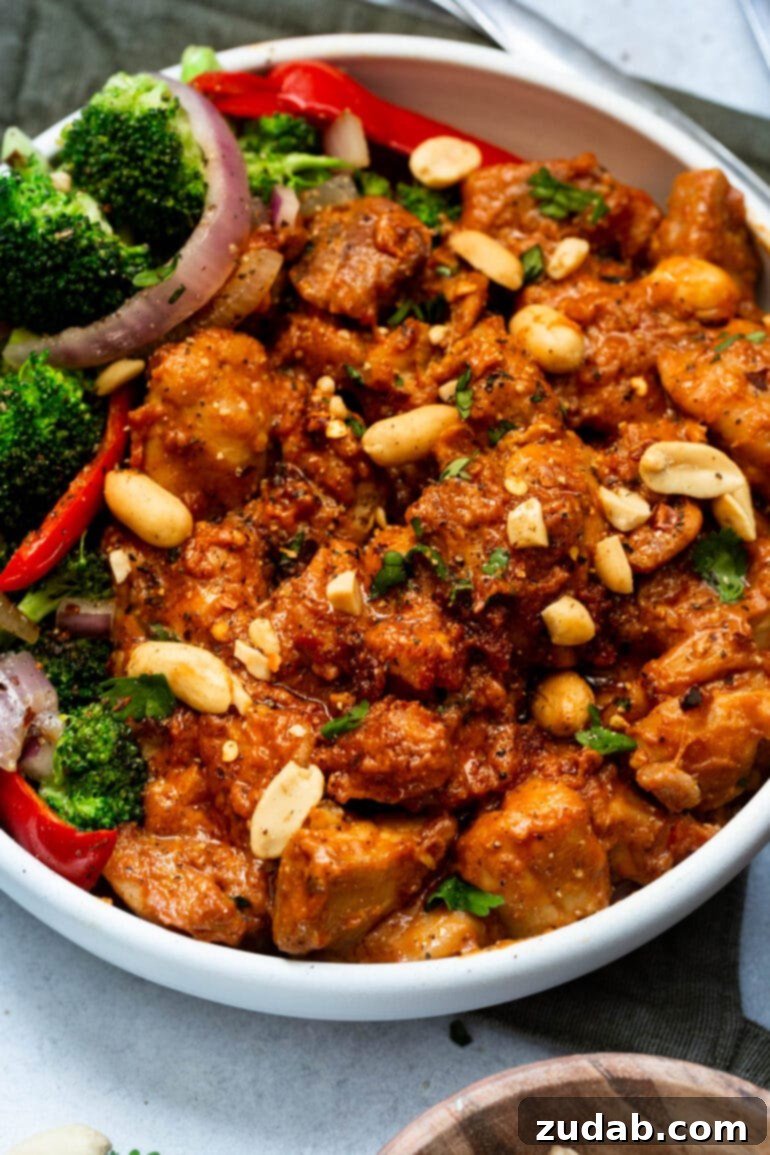 Irresistible Peanut Butter Chicken 9 a photo of a serving of peanut butter chicken topped with cilantro and chopped peanuts with a side of broccoli salad