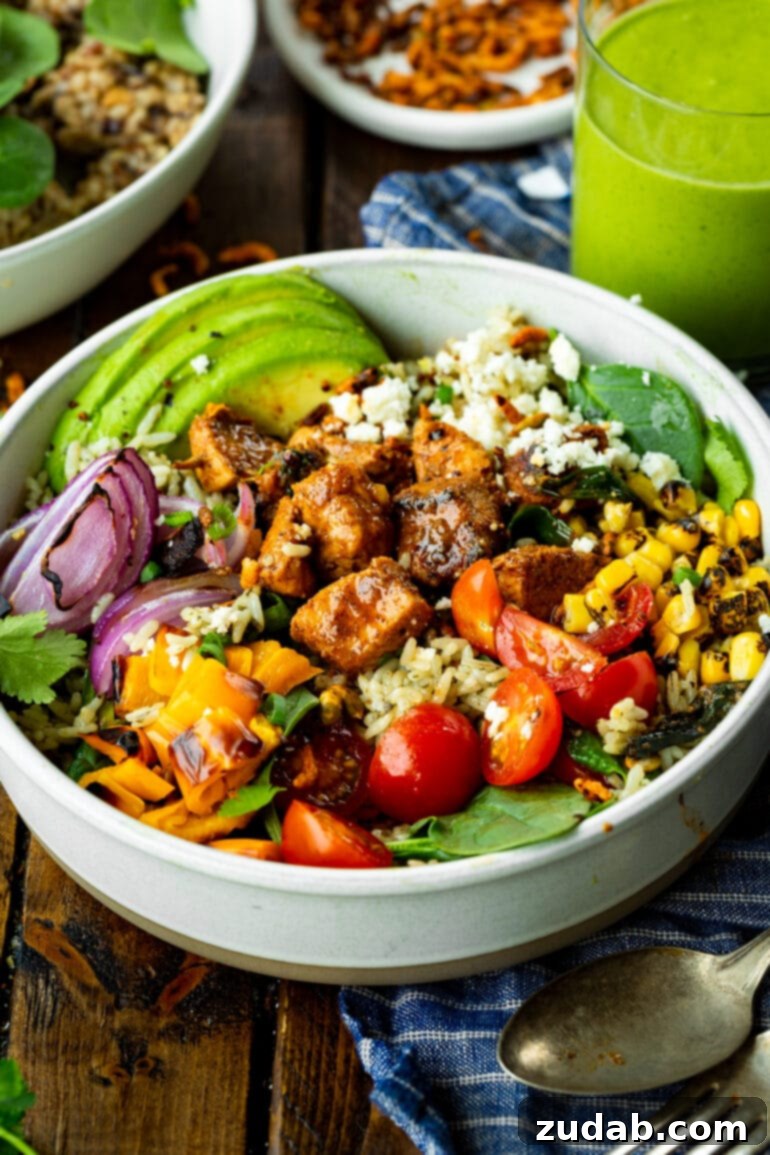 Fiesta Chicken Bowl 5 A vibrant and appealing burrito rice bowl, generously topped with savory sticky Mexican chicken, juicy cherry tomatoes, golden charred corn, crisp red onions, creamy avocado slices, and finished with a sprinkle of crumbled queso fresco.