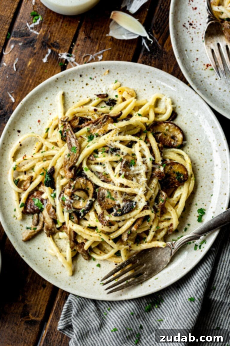 Velvety Creamy Mushroom Pasta 3 a photo of a plate loaded with a serving of creamy mushroom pasta with a fork sitting on the side of the pasta.
