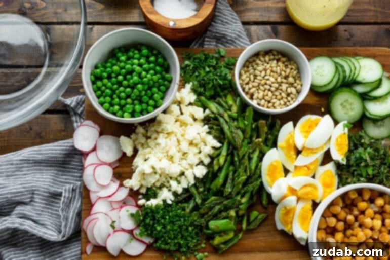 Effortless Springtime Greens 4 a photo of all the ingredients for an easy spring salad including asparagus, quartered hard boiled eggs, sliced radishes, a bowl of peas, toasted pine nuts and chopped fresh herbs.