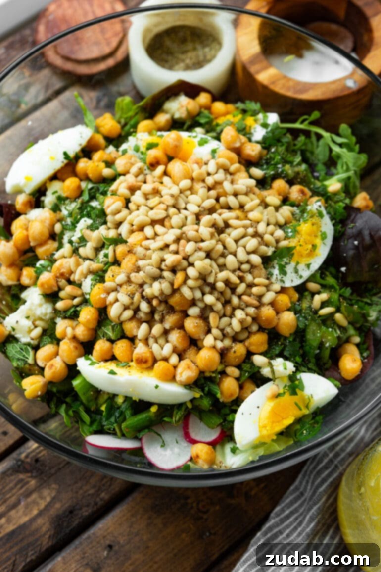 Effortless Springtime Greens 5 a photo of a large glass bowl full of all the ingredients for a spring salad that hasn't been tossed yet.