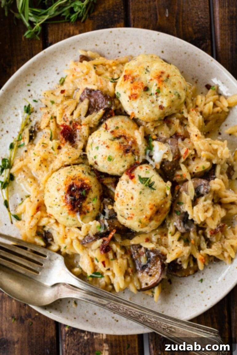 Golden Baked Chicken Meatballs and Orzo 2 A photo of creamy mushroom orzo topped with golden, herb-infused chicken meatballs.