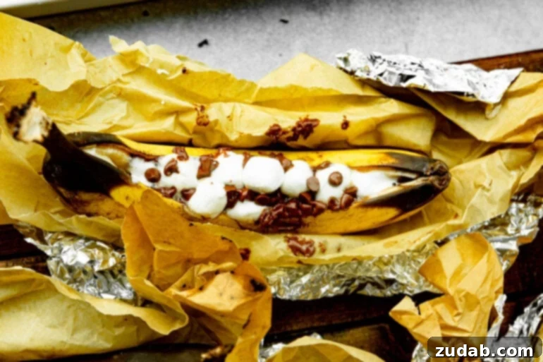 Ultimate Campfire Banana Boats 3 A ripe banana, carefully sliced down the middle and overflowing with mini marshmallows and chocolate chips, nestled in aluminum foil, awaiting its campfire roasting adventure.
