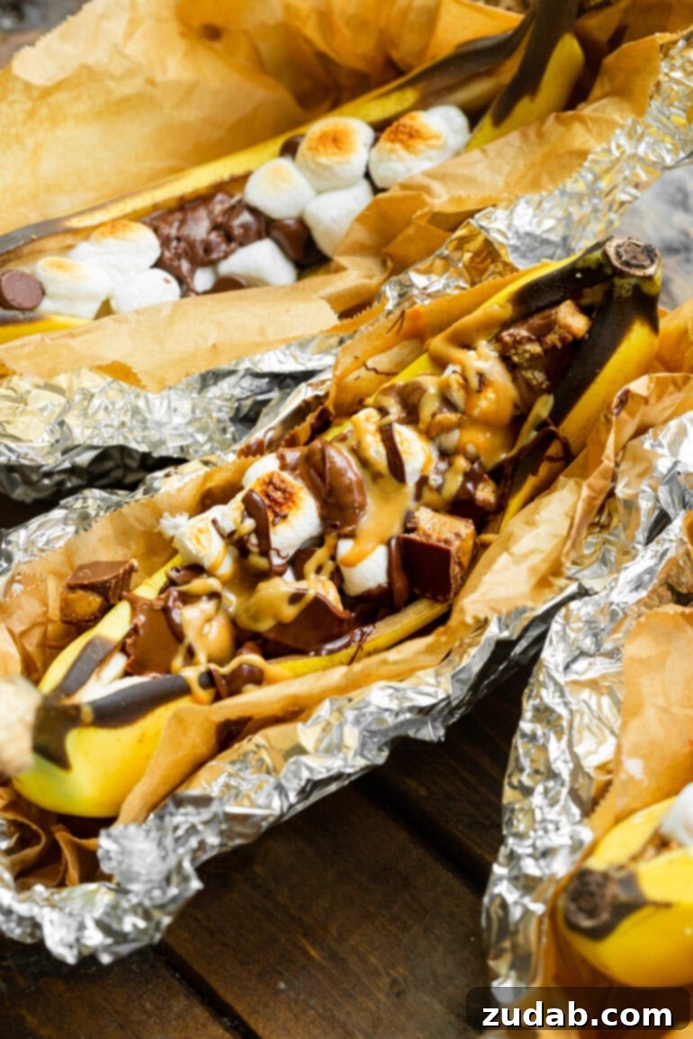Ultimate Campfire Banana Boats 4 A richly indulgent Reese's banana boat, showcasing a roasted banana filled with chopped Reese's Peanut Butter Cups, gooey melted marshmallows, drizzled with peanut butter sauce and hot fudge.