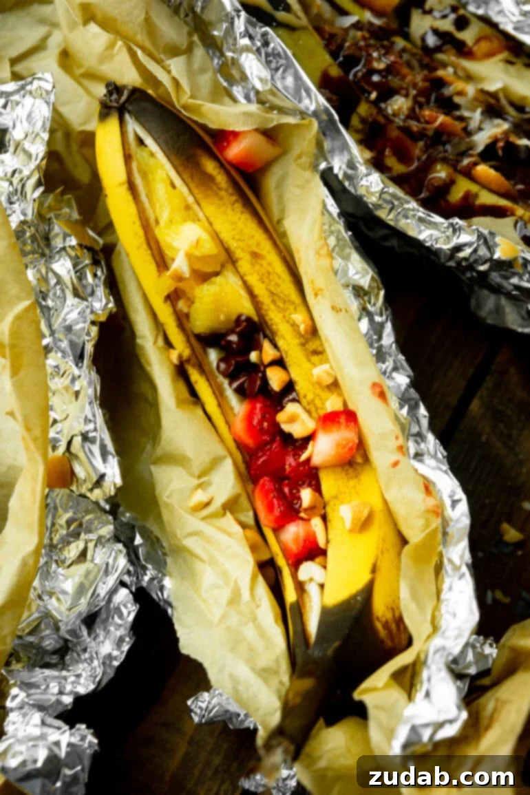 Ultimate Campfire Banana Boats 6 A beautifully roasted banana boat featuring banana split inspired toppings, including fresh sliced strawberries and a generous sprinkle of chocolate chips, glistening and ready to eat.