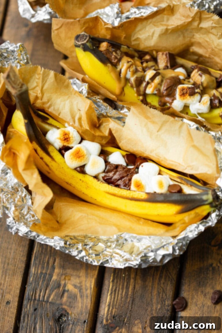Ultimate Campfire Banana Boats 7 A close-up shot of a perfectly charred campfire banana boat, resting on aluminum foil, filled with irresistibly gooey melted marshmallows and luscious chocolate chips.