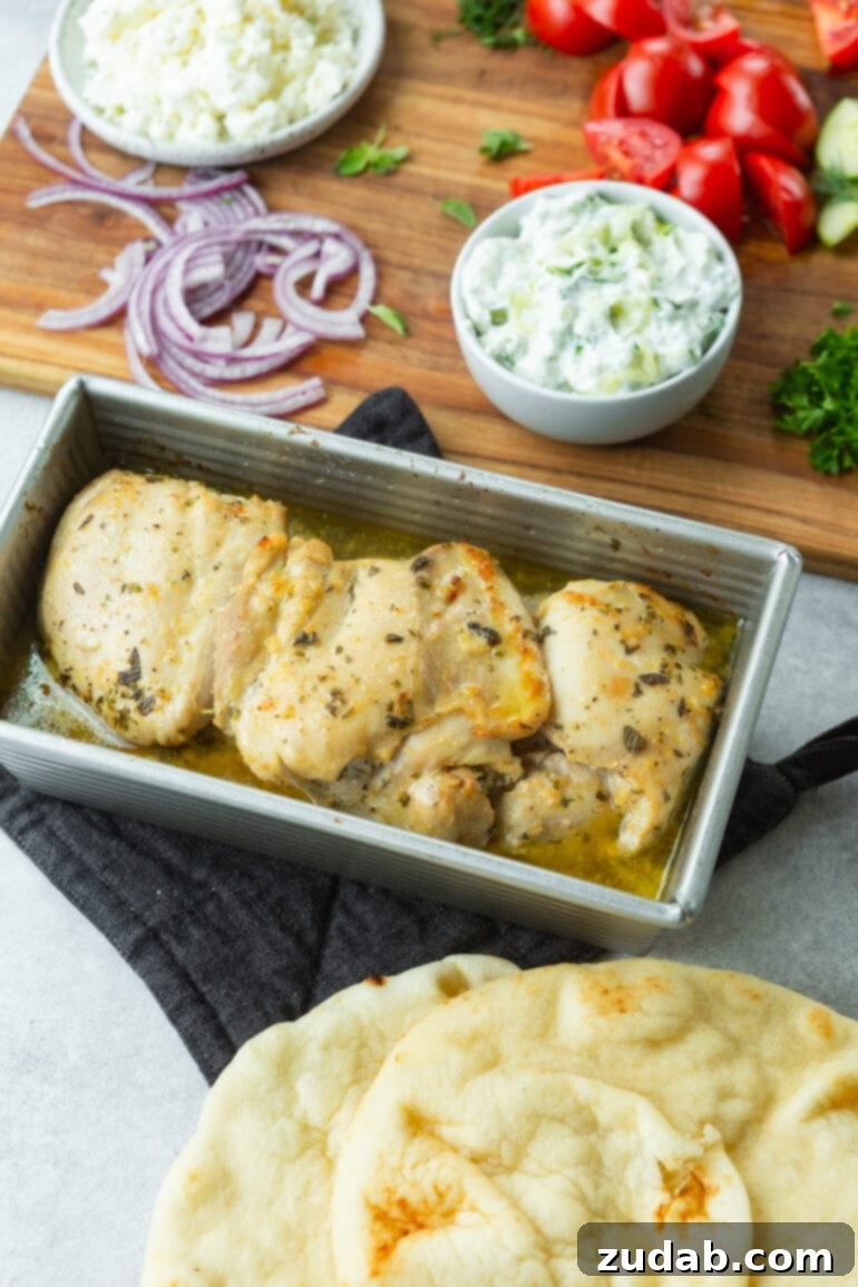 Cades Signature Chicken Gyros 6 A photo showcasing several baked chicken thighs resting in a bread loaf pan, richly seasoned with herbs and spices. The chicken appears incredibly moist and flavorful, ready to be sliced for gyros.