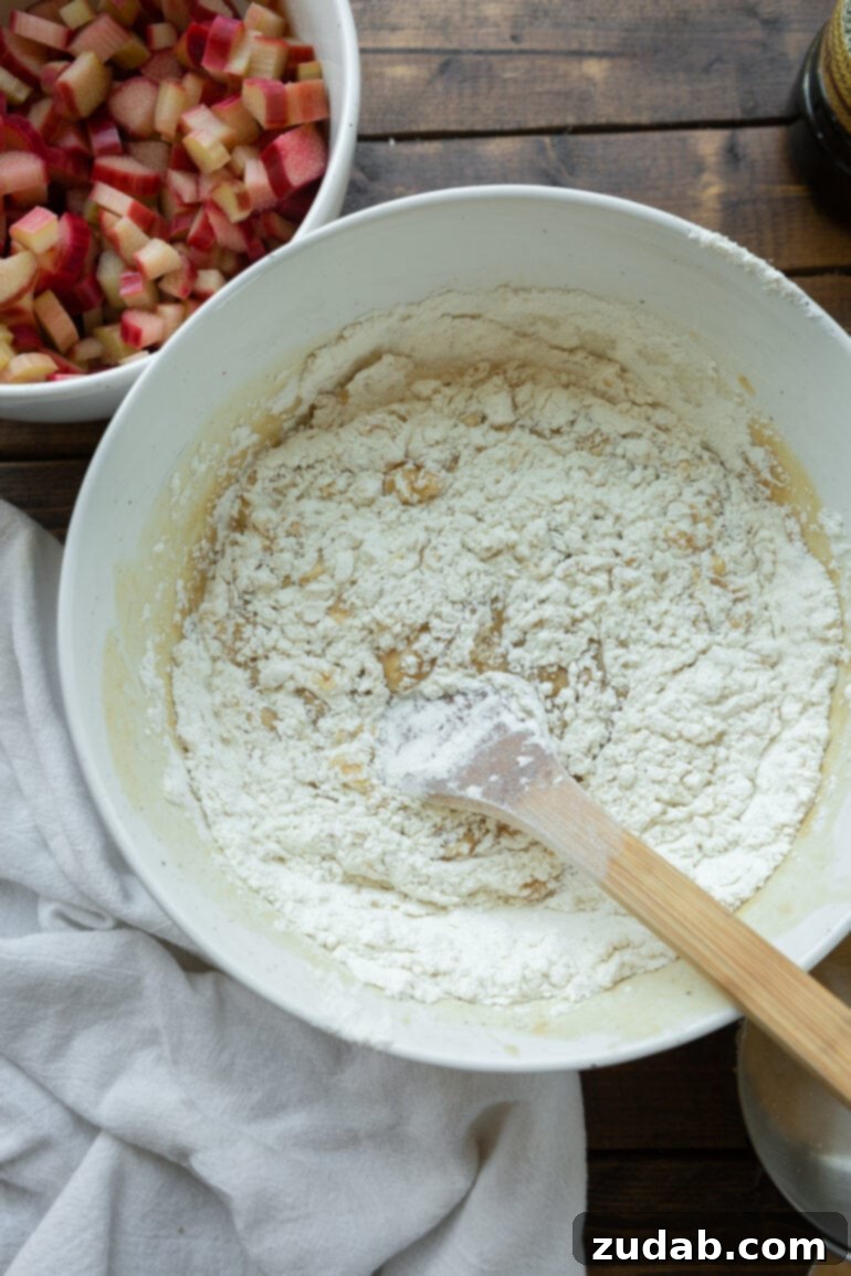 Sweet and Tart Rhubarb Cake 4 A photo of the dry ingredients for a cake being mixed in a bowl with a wooden spoon.