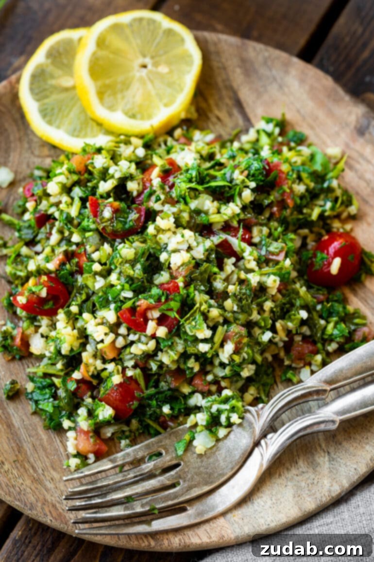 Bright and Flavorful Tabbouleh 2 A beautifully arranged serving of tabbouleh salad on a rustic wooden plate, garnished with fresh lemon slices and accompanied by two forks, emphasizing its fresh and inviting presentation.