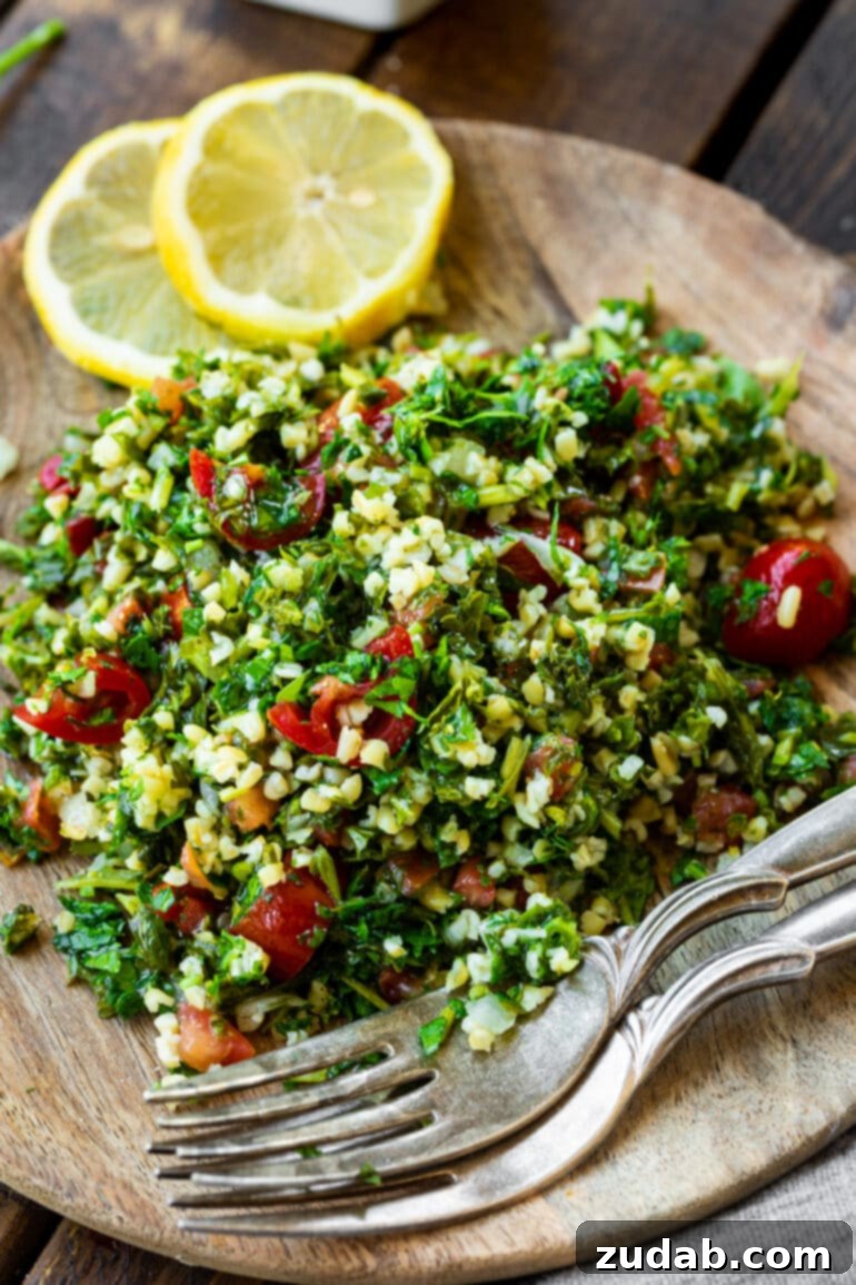 Bright and Flavorful Tabbouleh 5 A single serving of vibrant tabouli salad presented on a wooden plate, artfully arranged with lemon wedges and two forks, inviting you to taste its fresh appeal.