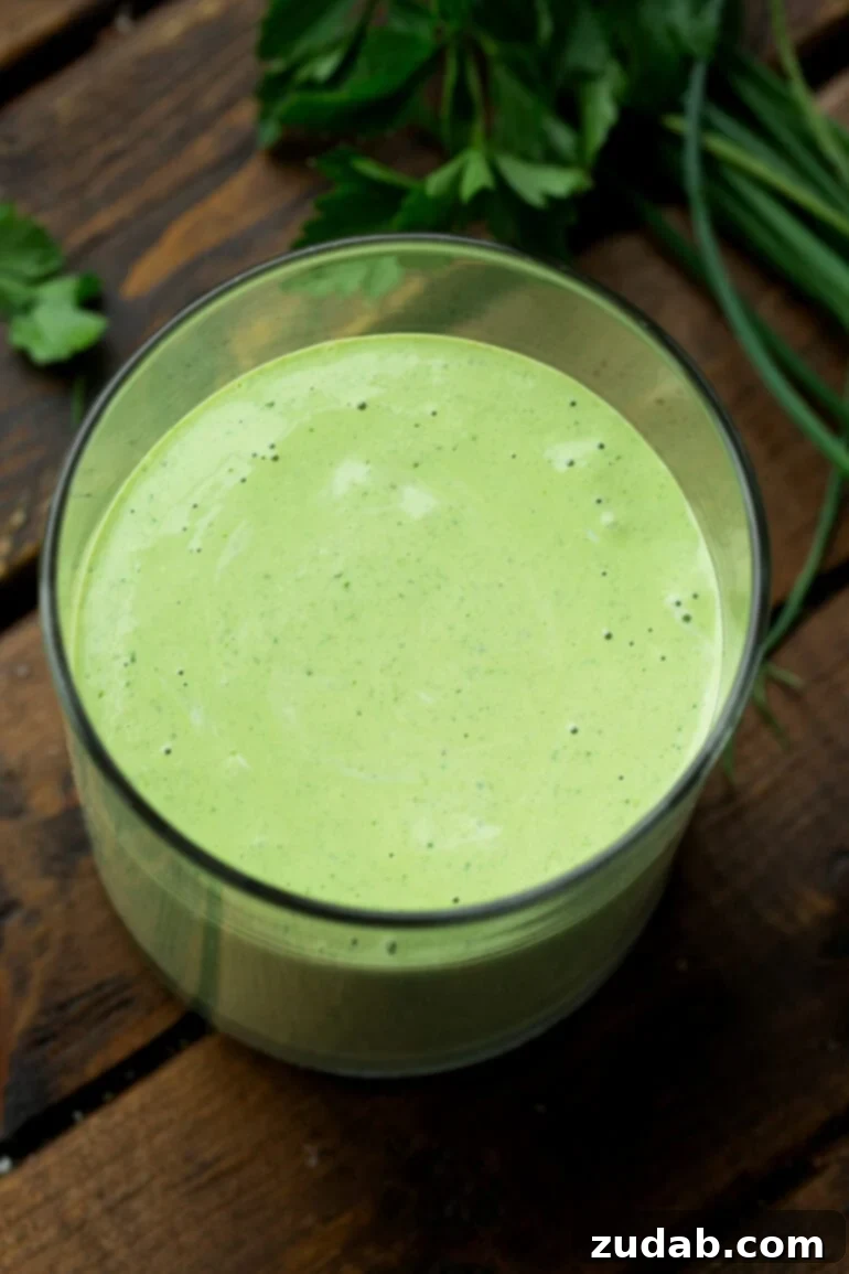 Velvety Basil Dressing Quick And Healthy 2 A clear glass container showcasing the rich, green hues of creamy basil salad dressing, ready to be drizzled over a fresh meal.