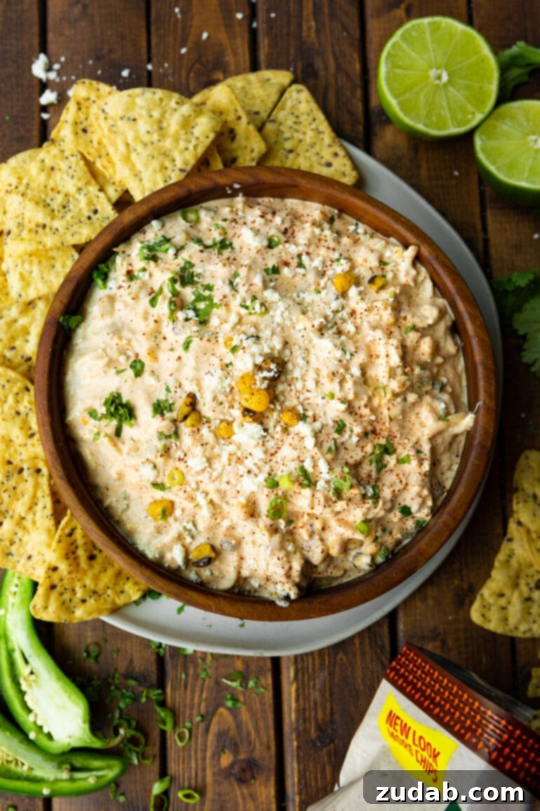 Irresistible Elote Dip 6 An inviting overhead shot of a rustic bowl of Mexican corn dip, generously surrounded by an assortment of crunchy tortilla chips, showcasing its irresistible appeal.