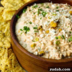 Irresistible Elote Dip 8 A photo of a large wooden bowl full of Mexican corn dip with tortilla chips scattered around the bowl.