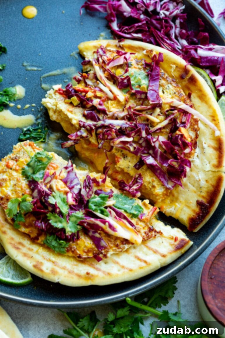 a photo of a piece of flatbread topped with a cooked ground chicken patty topped with coconut curry sauce, chopped radicchio and cilantro. The flatbread and chicken patty are broken apart.