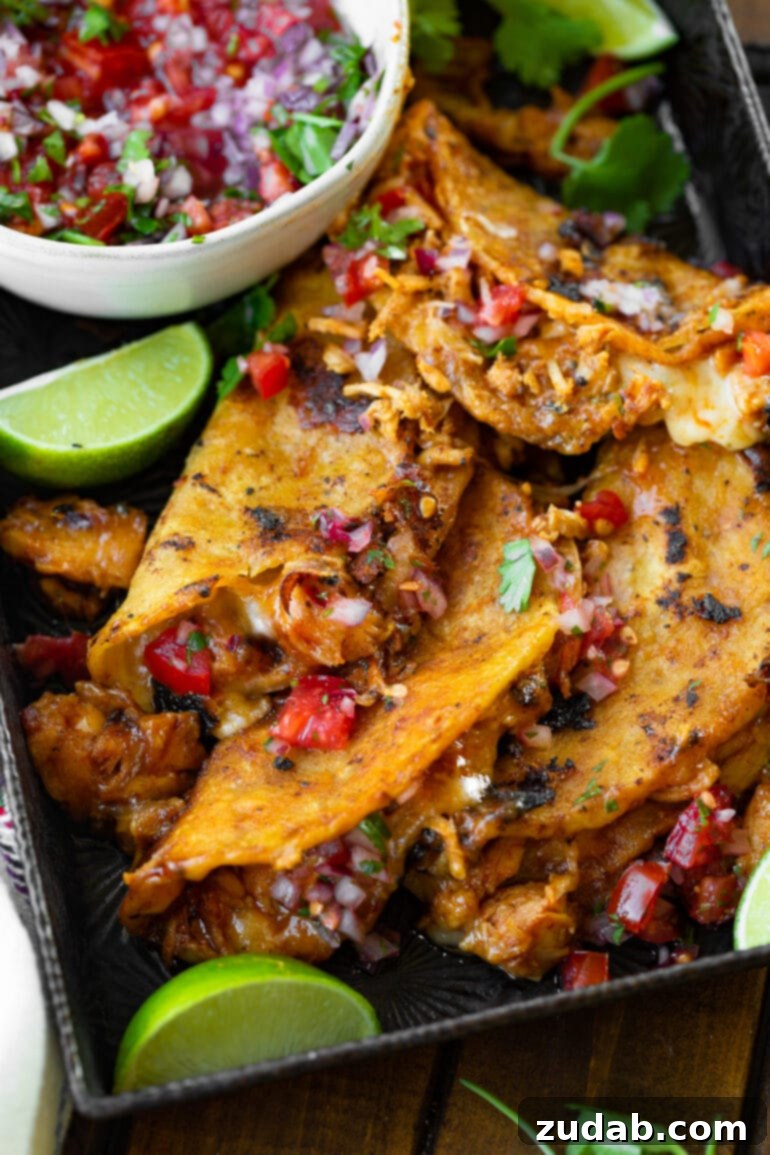 Ultimate Chicken Birria Tacos 4 An appetizing photo depicting a generous pile of crispy chicken birria tacos, beautifully arranged and topped with a vibrant homemade pico de gallo, ready to be enjoyed.