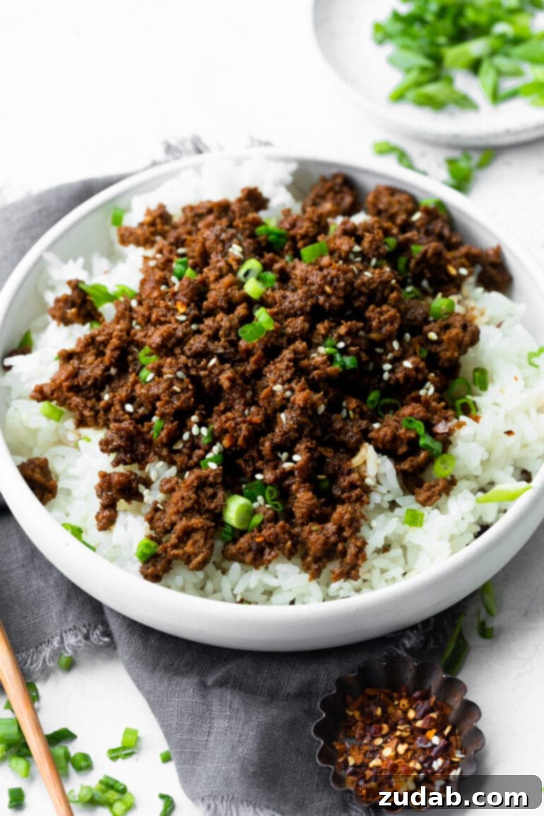 Effortless Korean Ground Beef 2 A vibrant photo of a bowl filled with steaming white rice, generously topped with savory Korean ground beef and a sprinkle of fresh green onions.