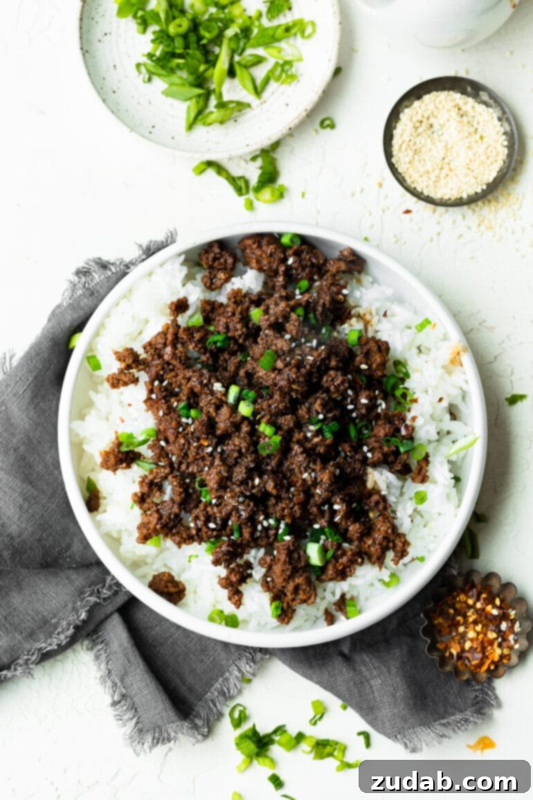 Effortless Korean Ground Beef 3 A high-angle shot showcasing a large, inviting bowl of fluffy steamed white rice, generously adorned with savory, glistening Korean ground beef.